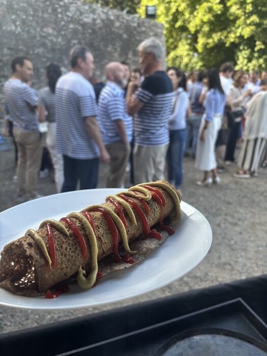 Traiteur convivial à Nantes cuisinant des saucisses sur une plancha géante lors d'une animation culinaire en plein air.