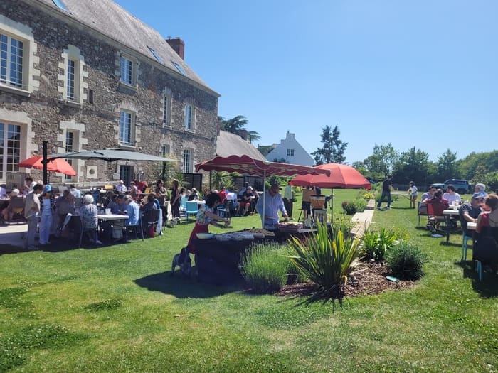 Service traiteur pour particulier lors d'une grande réception ensoleillée en plein air avec de nombreux invités.