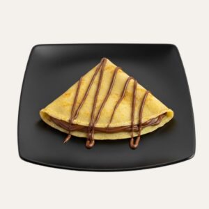 Crêpe maison au Nutella pliée en triangle, servie sur une assiette carrée noire.