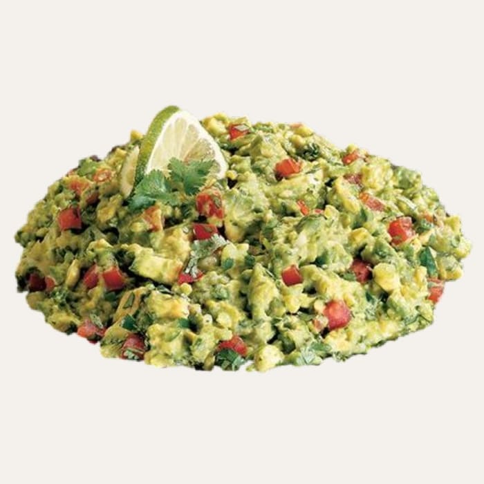 Guacamole brésilien - Traiteur Événementiel Nantes & Vitré | Restonomade Bol de guacamole frais avec morceaux d'avocat, dés de tomate, coriandre et un quartier de citron vert.