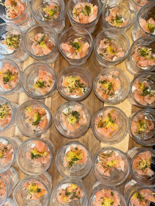 Vue de dessus de nombreuses verrines de tartare de saumon frais, décorées d'aneth et de zeste de citron.