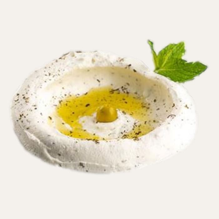 Labne du levant - Traiteur Événementiel Nantes & Vitré | Restonomade Bol de labné frais et onctueux, garni d'huile d'olive, d'une olive et d'une feuille de menthe.