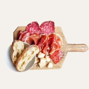 Planche de charcuterie variée avec jambon sec, saucisson, et pain sur une planche en bois.