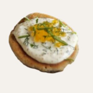 Bouchée apéritive asiatique "Racines d'Asie" à Nantes, servie sur un blini et garnie d'une crème d'edamame et d'une tranche de radis noir