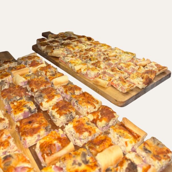 Assortiment de quiches maison en parts carrées, présentées sur des planches en bois pour un buffet.