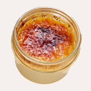 Crème brûlée à la vanille dans un pot en verre, avec une croûte de sucre caramélisée et craquante.