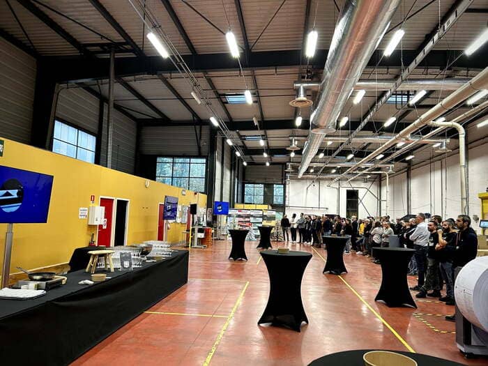 Buffet de traiteur événementiel Nantes et mange-debout noirs installés pour une réception d'entreprise dans un grand local industriel.

